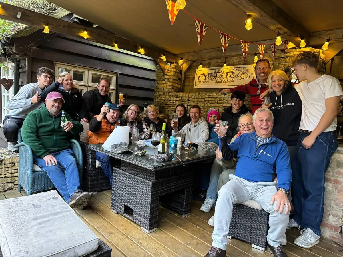 Members and friends raising glasses together under bunting and festoon lights at the clubhouse bar