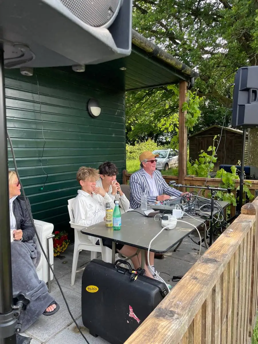 The commentary box beside the pavilion: mixing desk, microphones, speakers and the president at the controls in a striped blazer