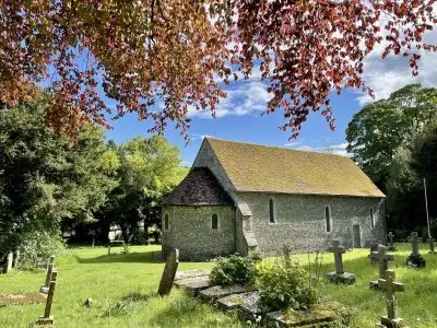 St Botolph's church, Swyncombe: flint walls and tiled roof among the trees and churchyard gravestones