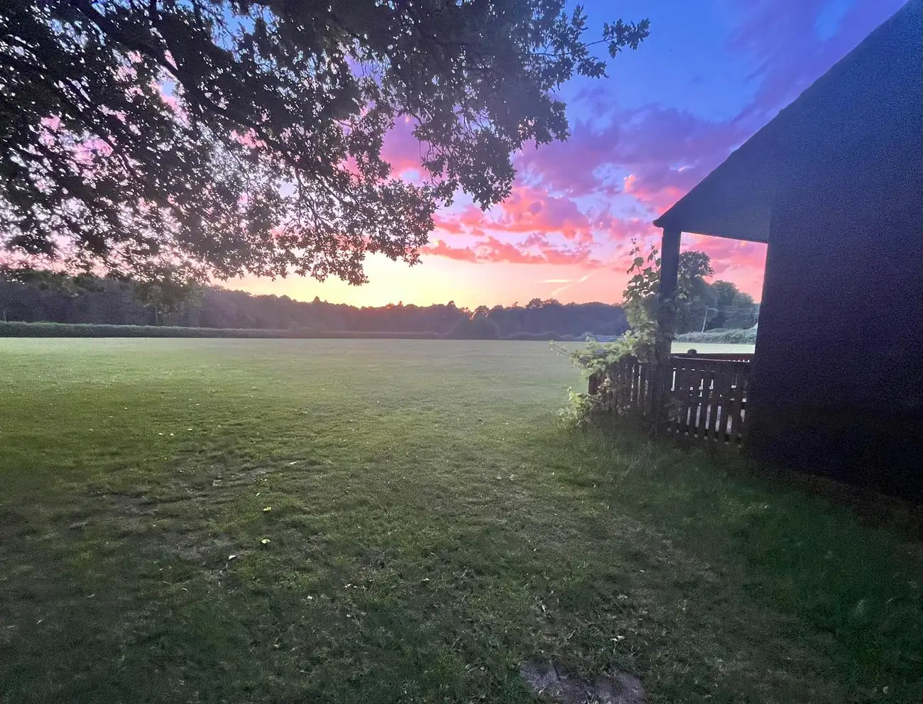 Sunset over the Field of Dreams: pink and violet sky above the outfield, seen from beside the pavilion